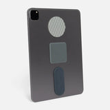 Grey tablet standing upright with three different textured silicone sensory stickers applied to its back.