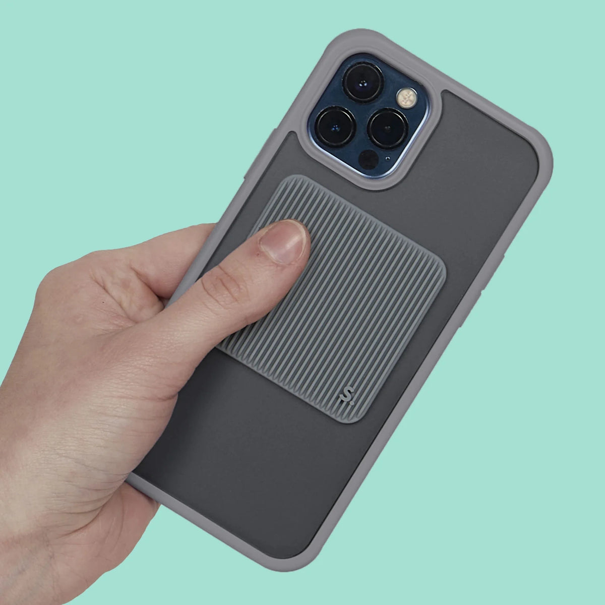 Hand holding a grey phone case with a square grooved silicone sensory sticker attached.
