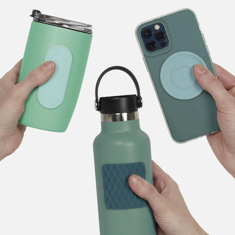 Hands holding a water bottle, mug, and phone case, each with a green silicone sensory sticker.