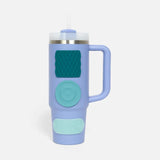 Light blue insulated travel tumbler with three silicone sensory stickers in varying shades of green attached to its side.