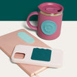 Pink insulated mug, notebook, and phone case featuring silicone sensory stickers in teal and green tones.