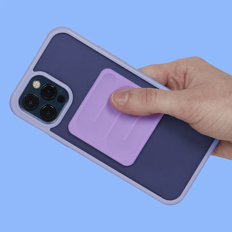 A hand traces the path of a square lavender silicone sensory sticker on a phone case.