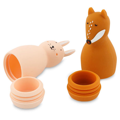 Two silicone containers shaped like animals: a pink rabbit lying open on its side and an upright orange fox. Both have removable lids.
