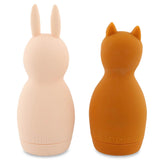 Two soft silicone bottles shaped like animal figures. The left is light pink with bunny ears, and the right is brown with cat ears. Both have a smooth texture and a playful tone.