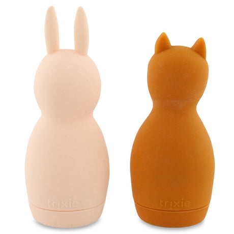 Two soft silicone bottles shaped like animal figures. The left is light pink with bunny ears, and the right is brown with cat ears. Both have a smooth texture and a playful tone.