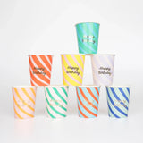 A pyramid stack of colorful striped paper cups that say "Happy Birthday" in gold script.