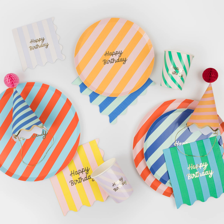 Colorful striped birthday party tableware set including plates, cups, napkins, and party hats.
