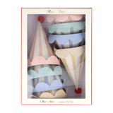 A box of Meri Meri pastel striped party hats with scalloped edges and red pom-poms.