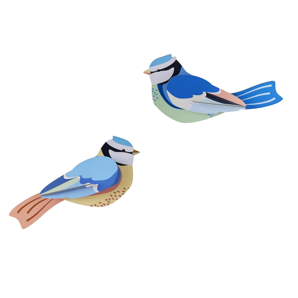 Two colorful, stylized paper birds with blue, green, and orange hues. The birds face opposite directions against a plain white background.