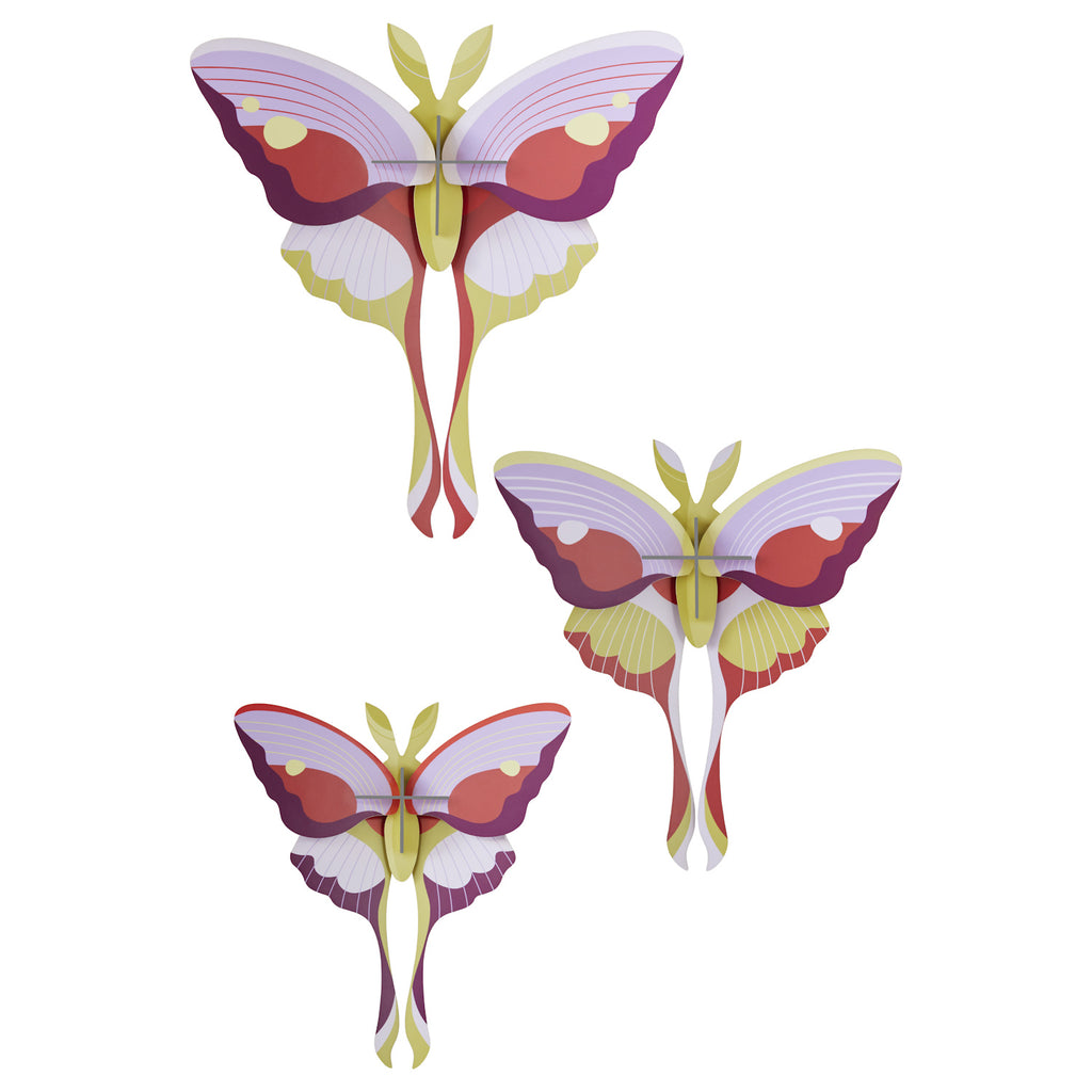 Three colorful, symmetrical butterfly sculptures with layered, geometric wings in shades of purple, pink, yellow, and red on a white background.