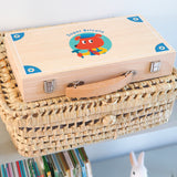 Super Bricolo wooden toy tool set case for children, resting on a woven wicker basket.