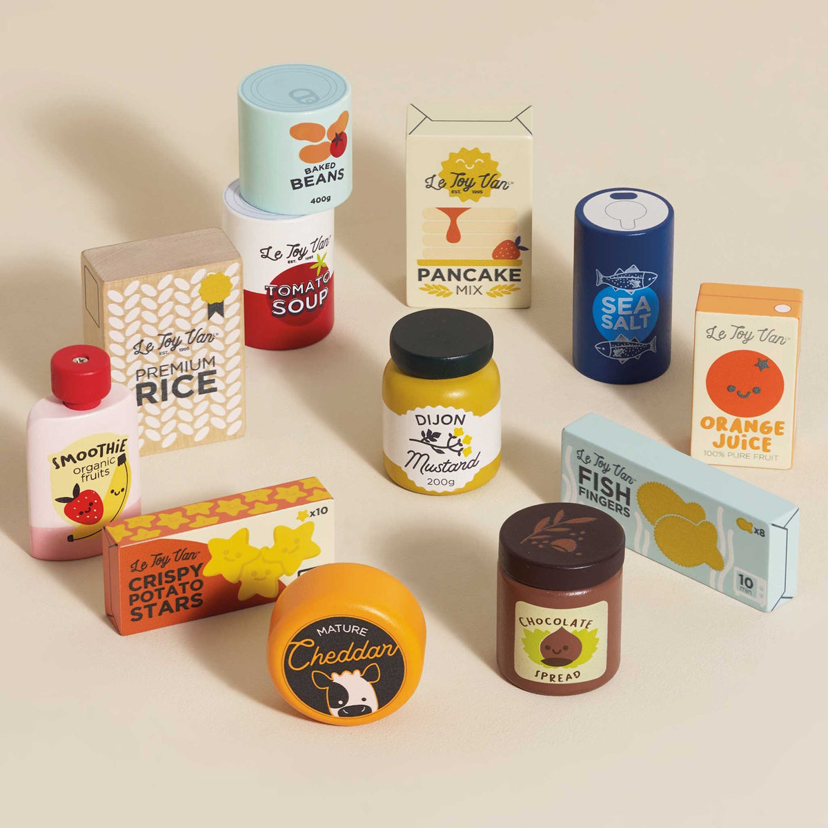 Wooden toy grocery items including rice, mustard, soup, and smoothie spread out on a beige surface.
