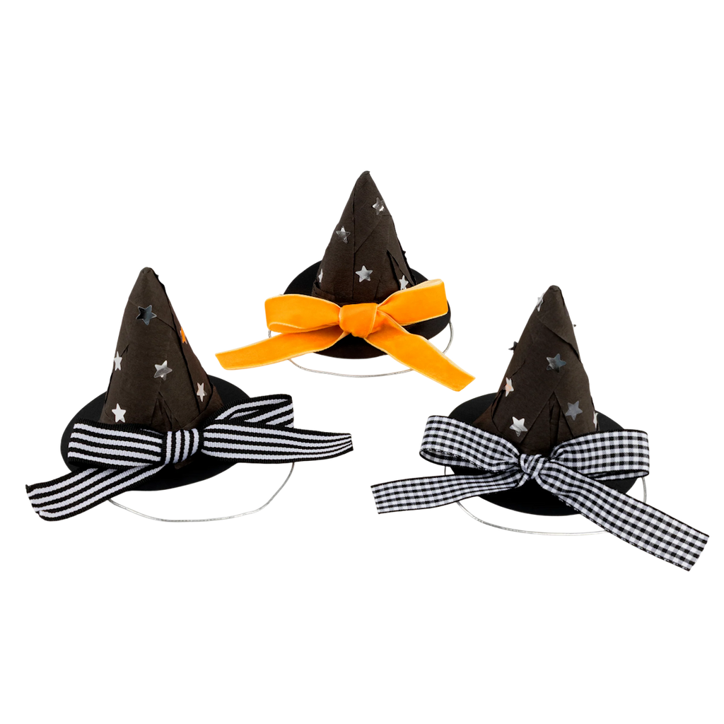 Three small, black witch hats with silver star patterns. Each hat features a different ribbon: orange, striped, and gingham, set against a white background.