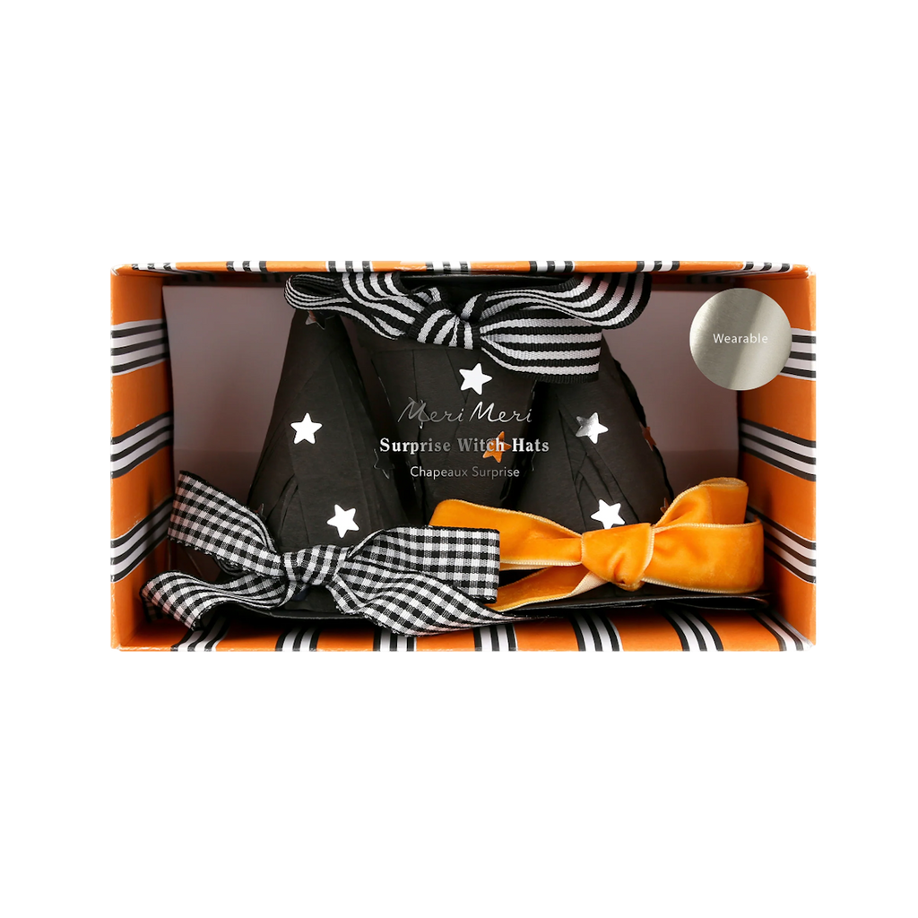 Festive box containing black witch hats adorned with white stars and striped black-and-white bows. Orange and black striped packaging evokes a Halloween theme.