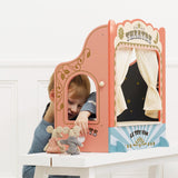 Young boy peeking out from behind a wooden tabletop puppet theatre with small mouse puppets.