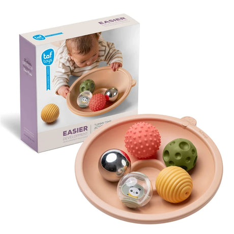 Taf Toys tummy time tray set with sensory balls next to product packaging showing a baby playing with it.