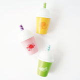 Flat lay view of three colorful wooden play smoothie cups with white domed lids and straws.