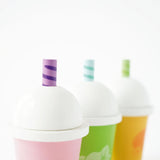 Close-up of three wooden play smoothie cups with white domed lids and striped straws.