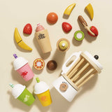 Wooden play blender, fruit pieces, and smoothie cups arranged flat on a beige background.
