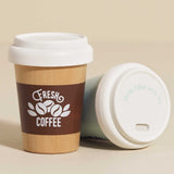 Wooden toy coffee cup standing next to another cup resting on its side, showing the white lid design.