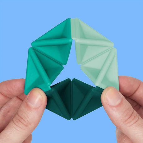 Hands flexing a teal silicone hexaflexagon fidget toy against a solid blue backdrop.