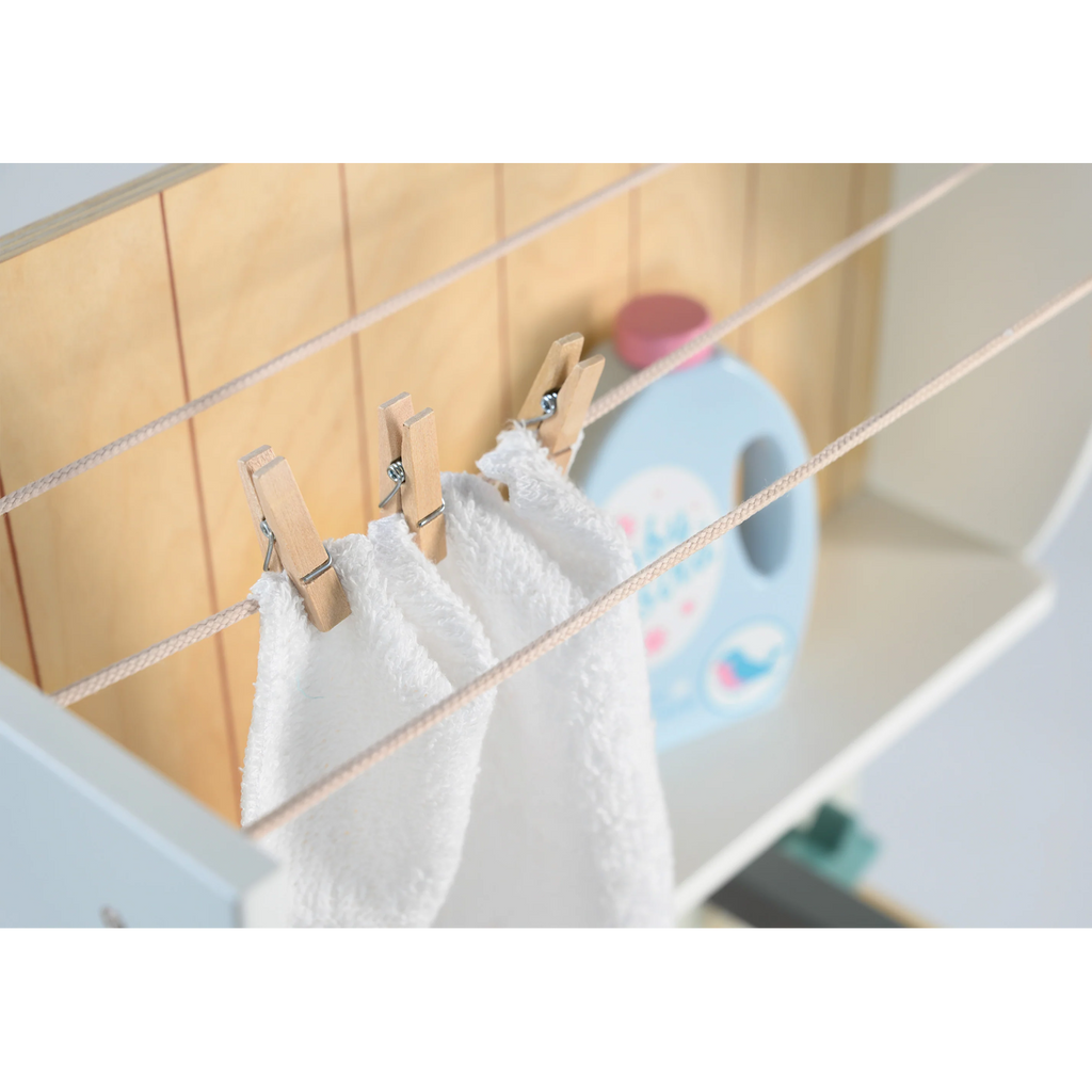 Wooden play set featuring a miniature washing machine, ironing board, and laundry accessories for imaginative role play and tidy-up fun.