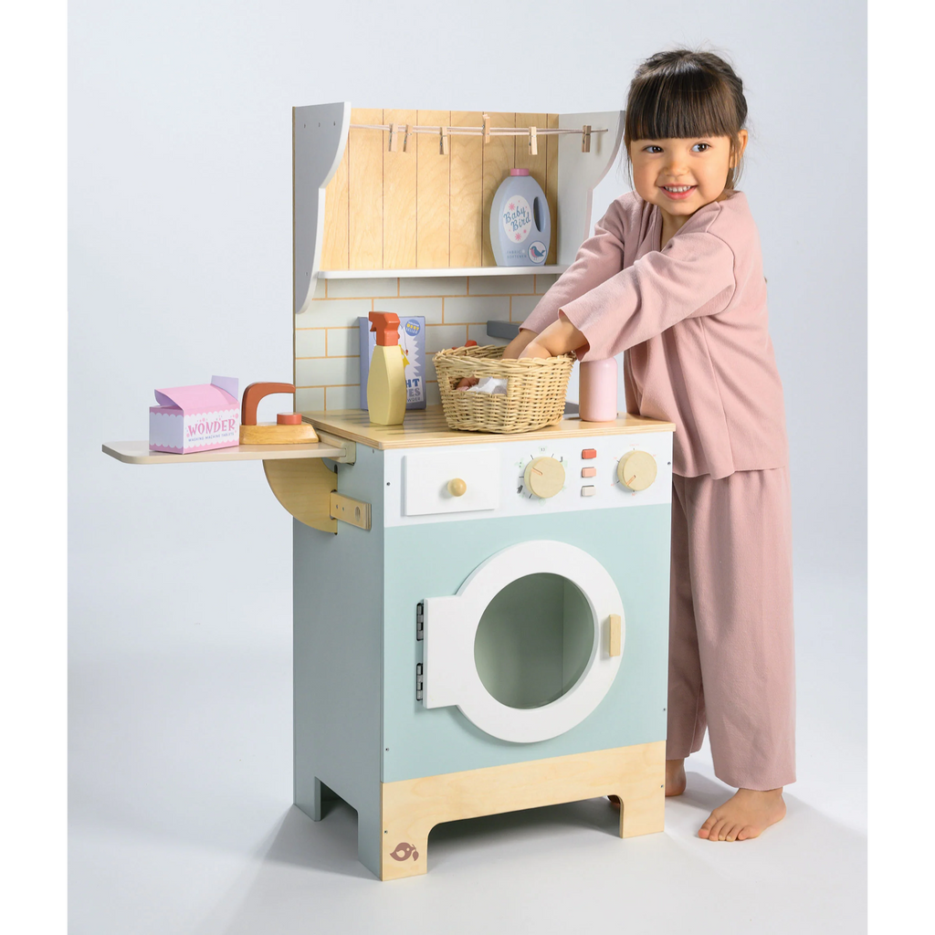 Wooden play set featuring a miniature washing machine, ironing board, and laundry accessories for imaginative role play and tidy-up fun.