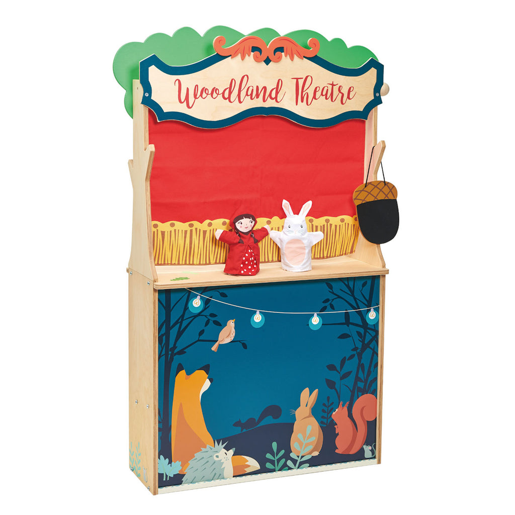 Colorful puppet theater with "Woodland Theatre" sign, featuring a red curtain. Two hand puppets, a girl in red and a white rabbit are displayed. The base shows a forest scene with animals like a fox, rabbit, and squirrel, under string lights. The tone is playful and whimsical.