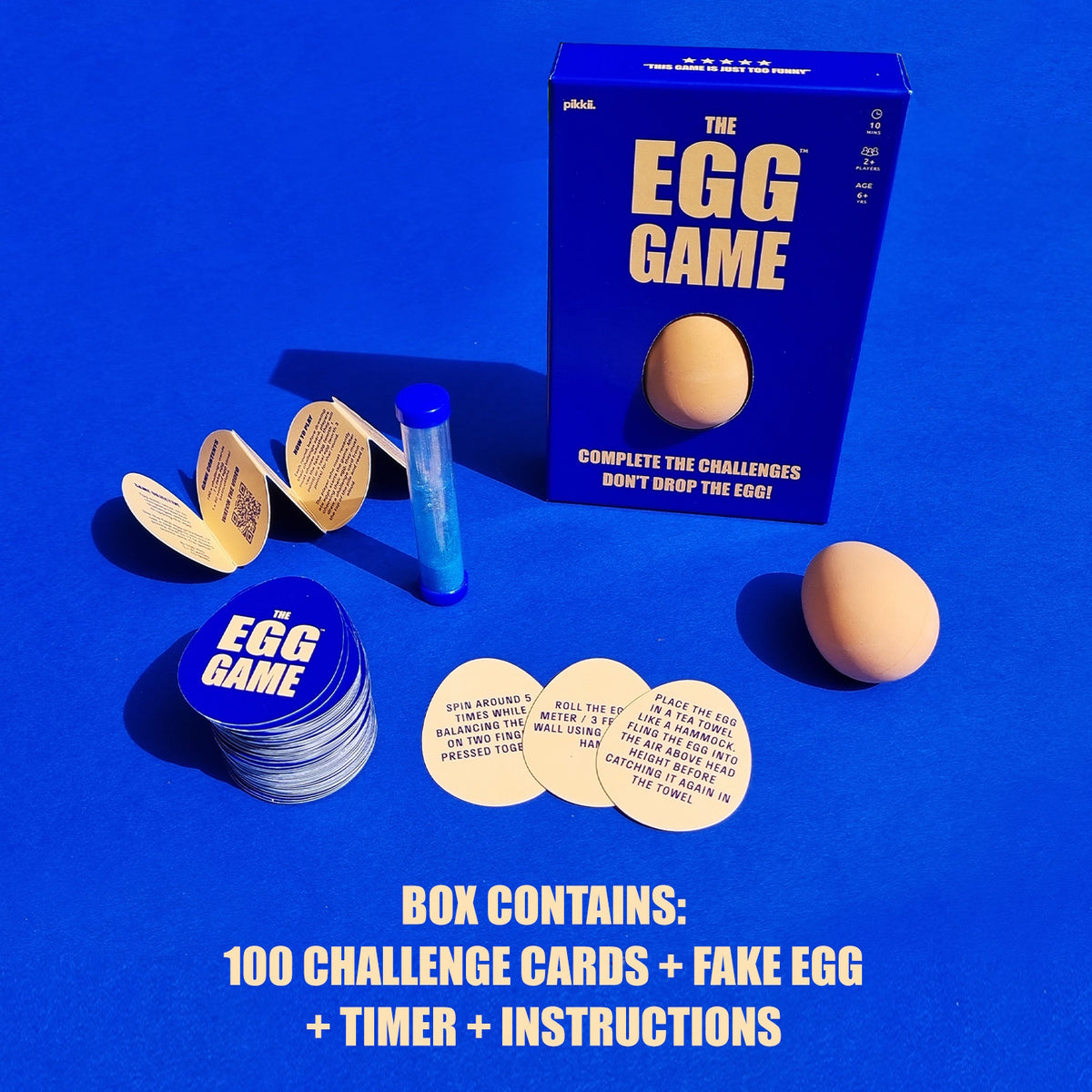 The Egg Game box displaying contents: fake egg, sand timer, instructions, and challenge cards.