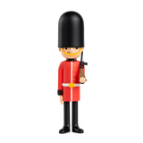 Toy soldier figure styled as a British royal guard in a red uniform and tall black hat, holding a rifle. Stands against a plain white background.