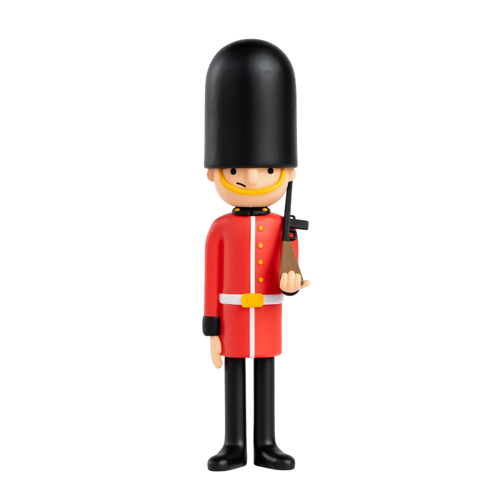 Toy soldier figure styled as a British royal guard in a red uniform and tall black hat, holding a rifle. Stands against a plain white background.