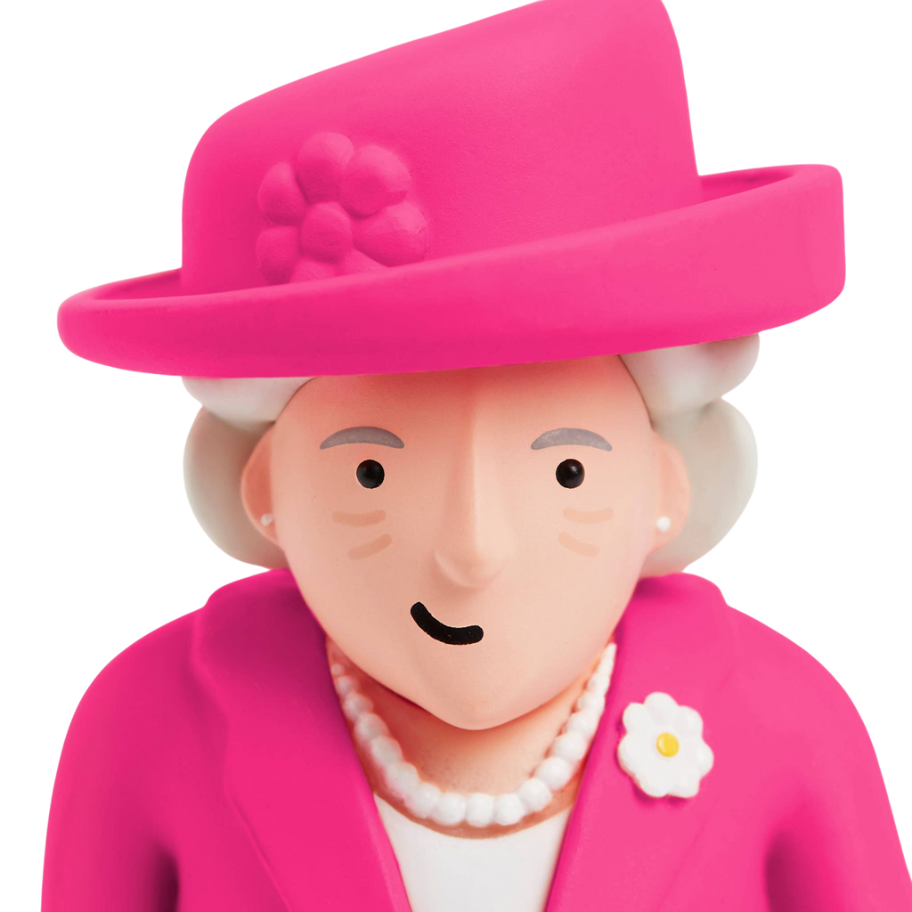 A playful figurine of an elderly woman wearing a vibrant pink hat and jacket, adorned with a flower pin and pearl necklace, set against a white background.