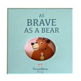 Light blue gift box for "As Brave As A Bear" cloth book showing a bear illustration through a oval window.