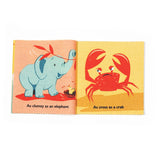 Open fabric book pages showing illustrations of an elephant and a crab with printed text captions.