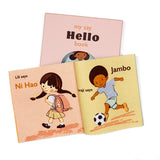 Open fabric book displaying children saying greetings in different languages, placed in front of its pink gift box.