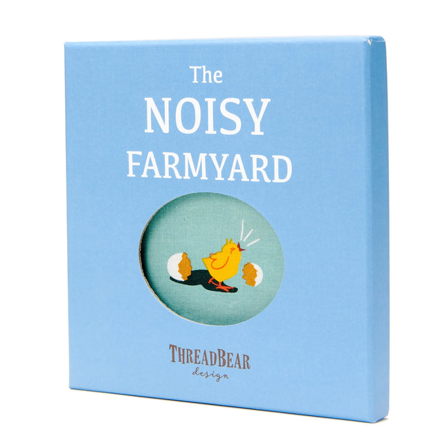 Light blue gift box for "The Noisy Farmyard" book with a chick hatching illustration in a circular window.
