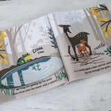 Open cloth book showing a frog by a pond and a deer with her fawn in the forest.