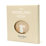 Square gift box titled "The Woodland Hush" with a circular cutout revealing a white rabbit illustration.