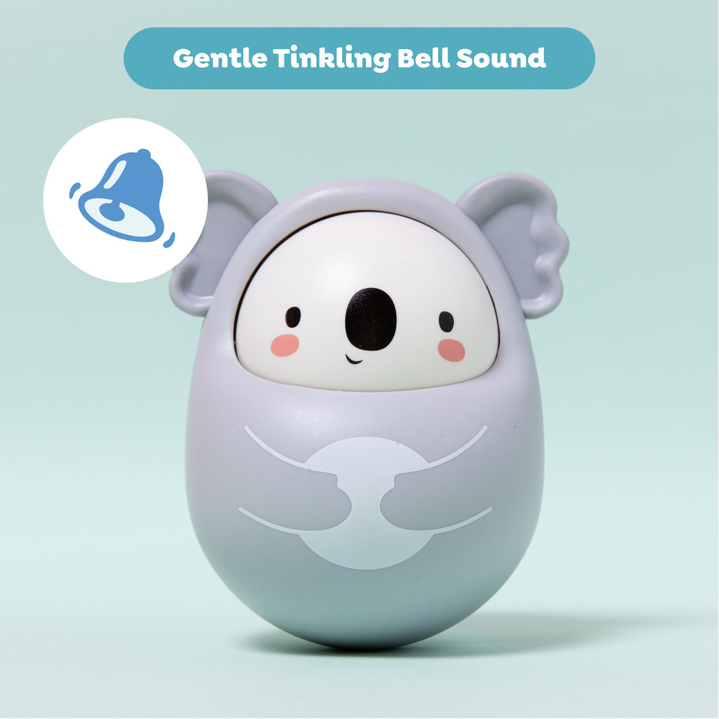 Cute, gray koala-shaped toy with a smiling face and blushing cheeks on a light teal background. Text reads "Gentle Tinkling Bell Sound." Bell icon on the left.