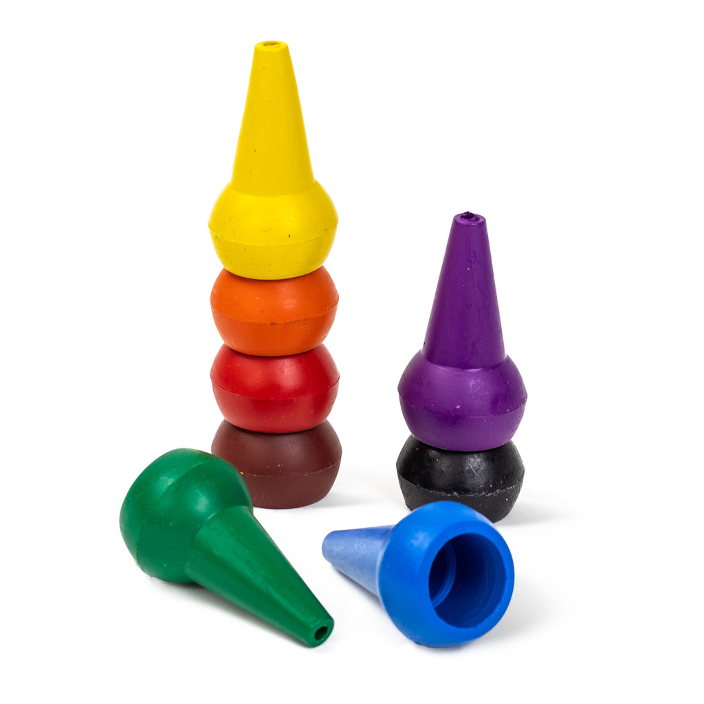 Stacked, cone-shaped crayons in yellow, orange, red, and brown stand upright. Nearby, purple, green, and blue crayons lie scattered on a white surface.