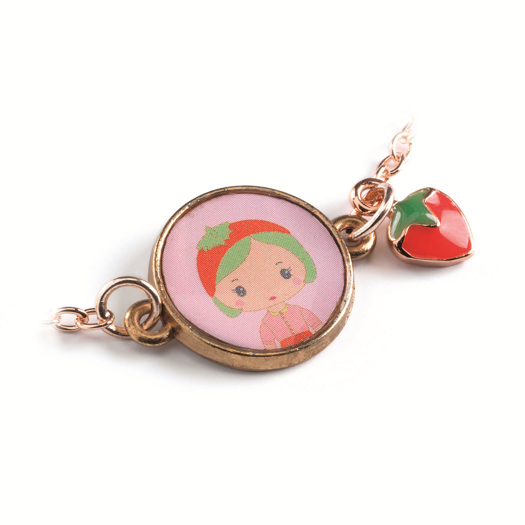 A children's bracelet from Djeco's Tinyly collection featuring a gold-colored chain and a charm of Berry, a character depicted with a strawberry accessory.