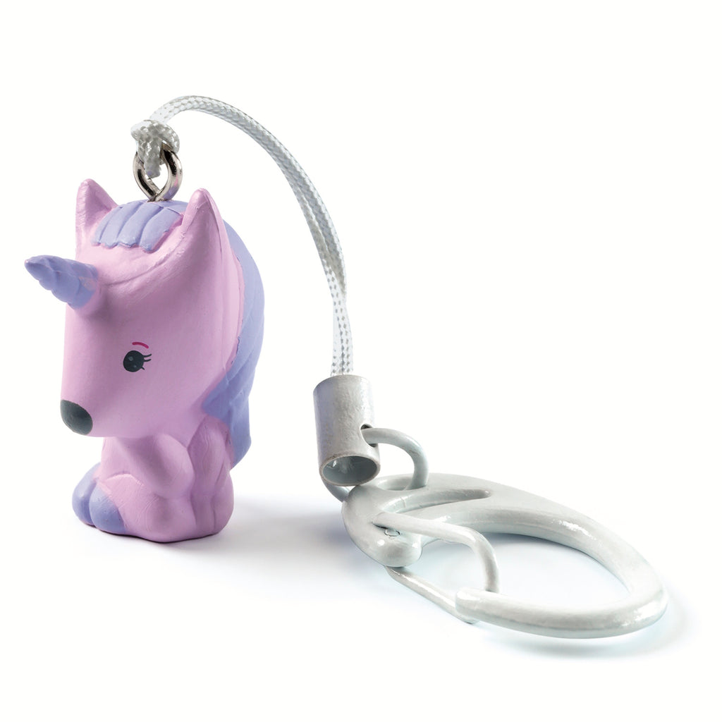 A purple unicorn-shaped charm with a blue mane, attached to a metallic clip by a white cord, on a plain background.