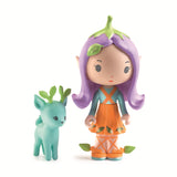 A colorful mushroom-shaped house with a doll peeking out, surrounded by a whimsical, illustrated landscape and a green toy deer. 