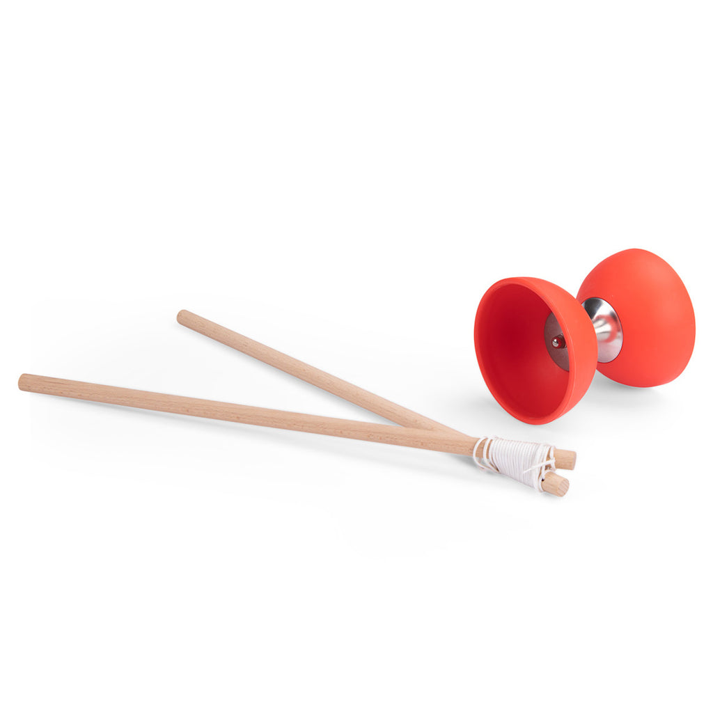 A red diabolo with wooden sticks wrapped in white string. The diabolo's metal center is visible. The setup suggests a playful, juggling activity.