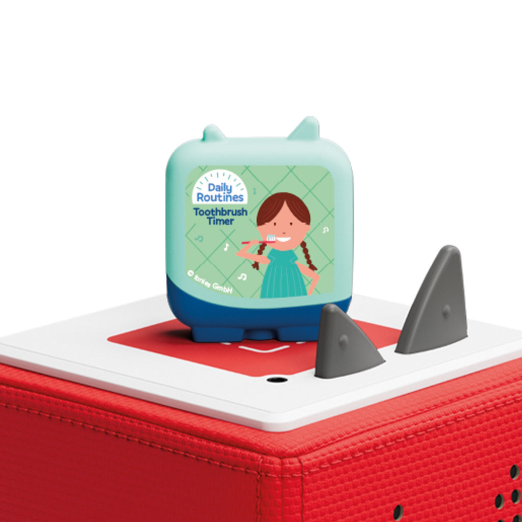 A cube-shaped device on a red base displays a cartoon girl brushing her teeth with the label "Daily Routines Toothbrush Timer," conveying a playful tone.