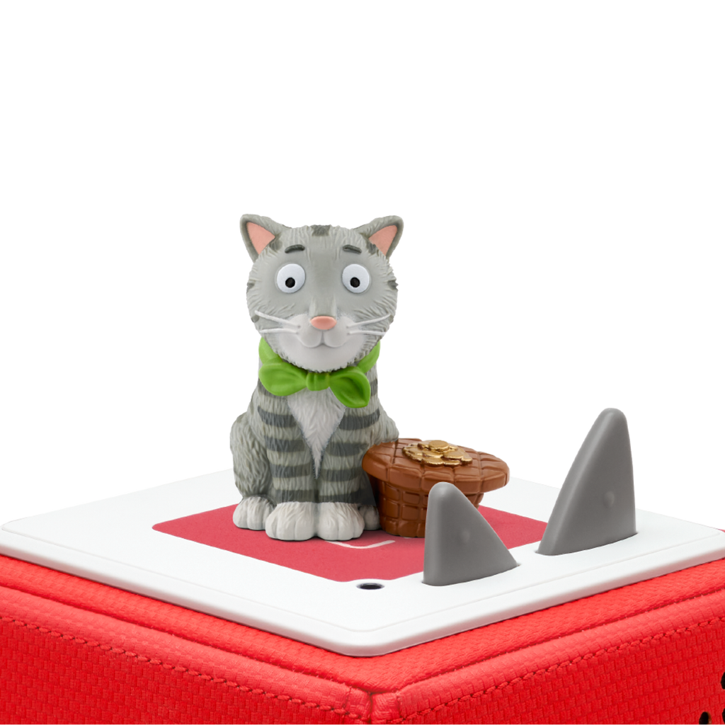 A cartoonish gray-striped cat figurine with a green bow tie sits beside a basket of gold coins on a red and white box, against a white background.