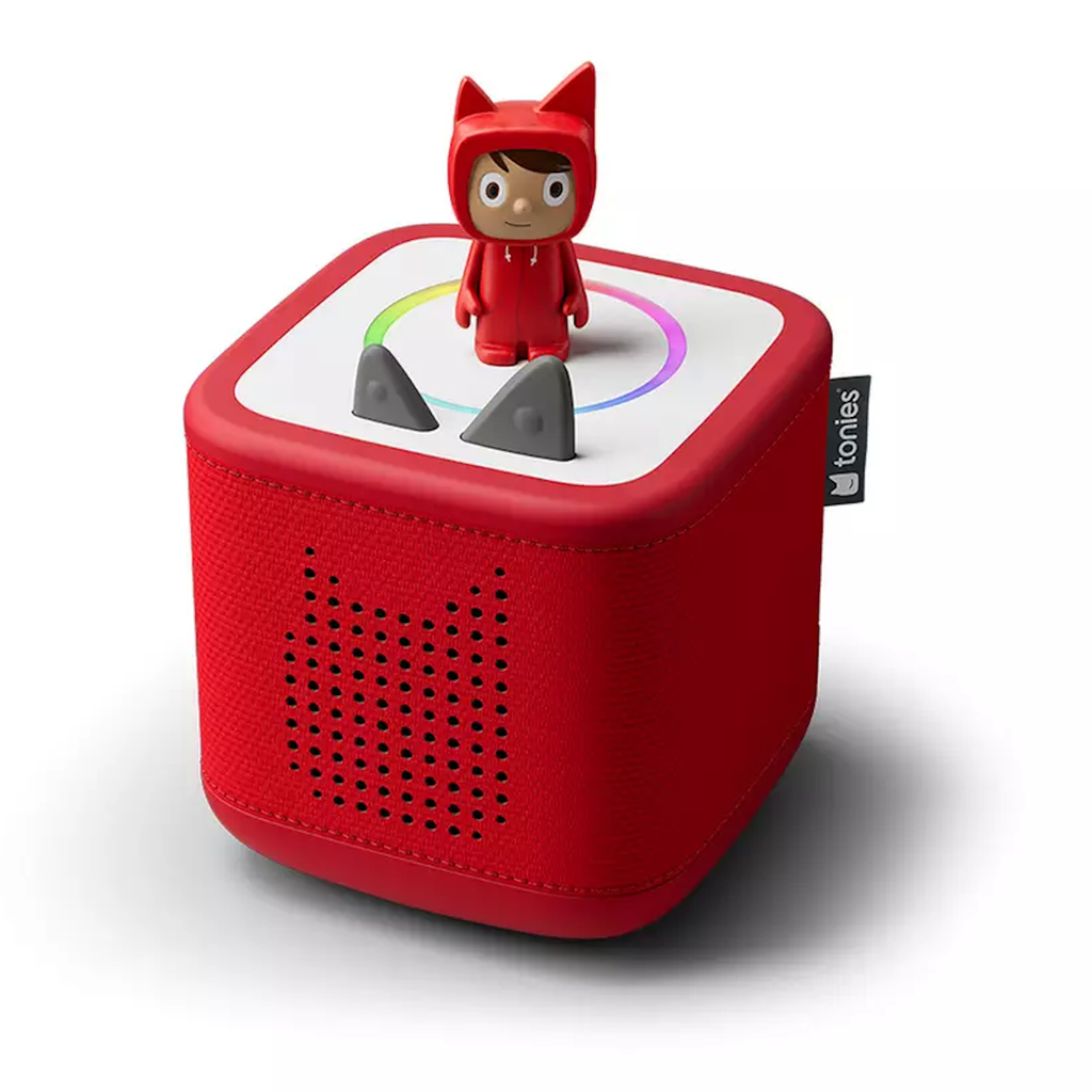 Red Toniebox with a small figurine wearing a red suit and cat ears standing on top. The box features speaker holes and gray volume controls.