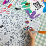 A child coloring an animal-themed activity mat with markers next to a "Born Bizzy" canvas bag.