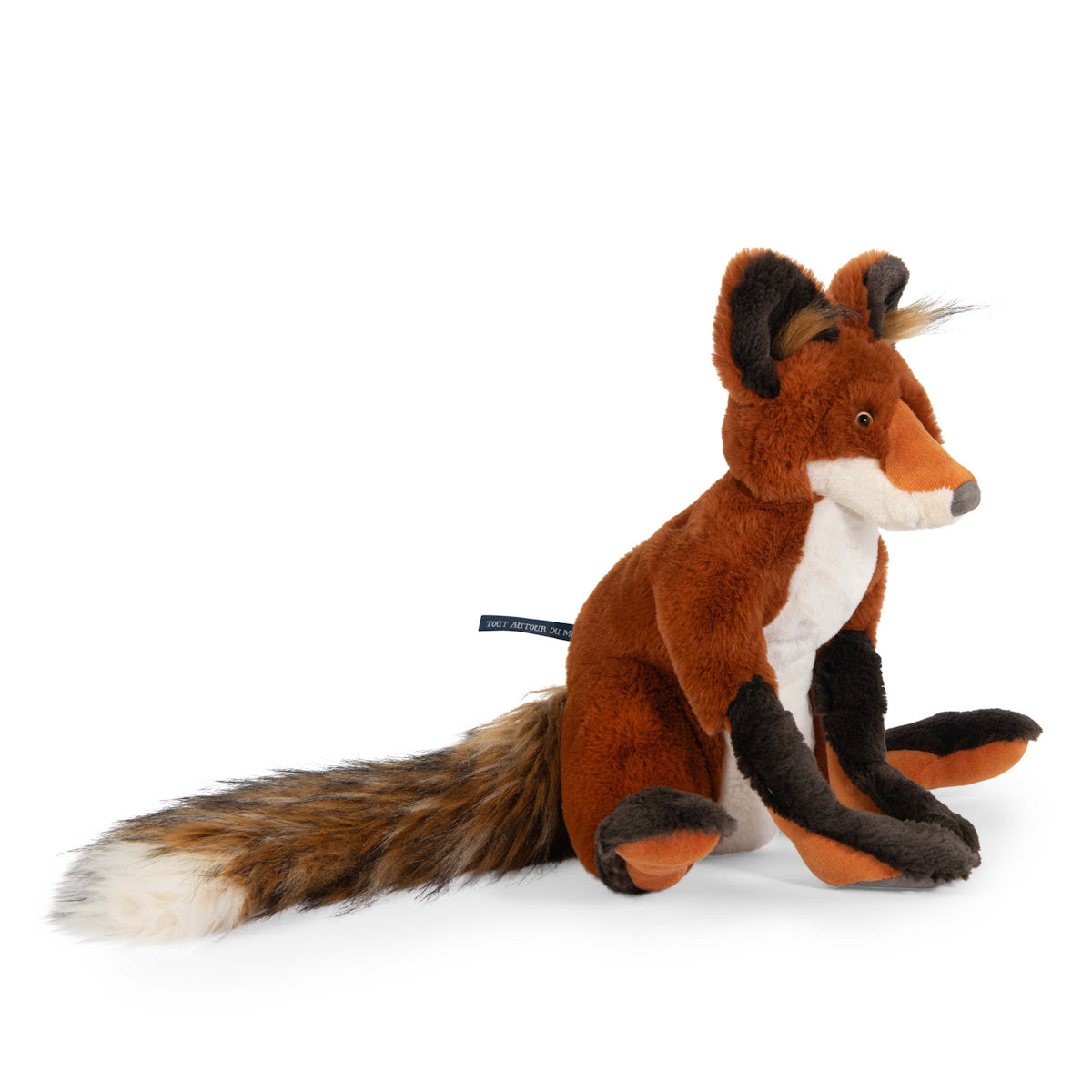 A plush fox toy sits upright on a white background. It has orange fur, a white belly, and dark brown paws. The fox's expression is friendly and playful.