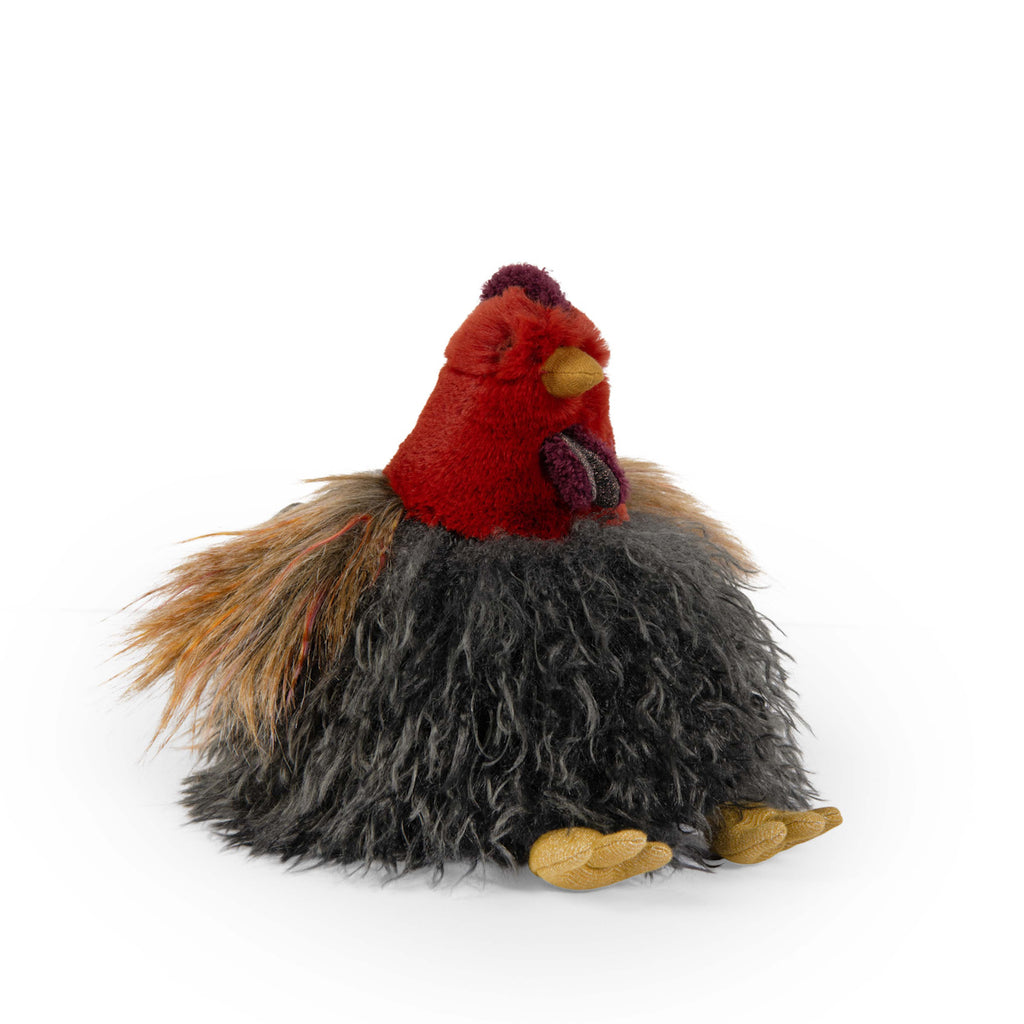 Fluffy plush chicken toy with a red head and yellow beak, featuring long, shaggy, black and brown body fur, sitting on a white background.